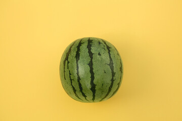 One whole ripe watermelon on yellow background, top view
