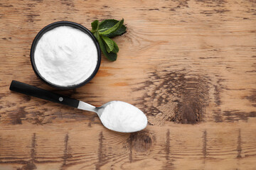 Sweet fructose powder and mint leaves on wooden table, flat lay. Space for text