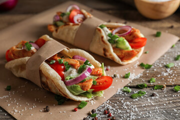 Fototapeta na wymiar Delicious pita wraps with meat and vegetables on wooden table, closeup