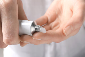 Woman squeezing out ointment from tube on her finger, closeup - obrazy, fototapety, plakaty