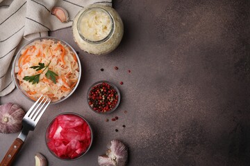 Delicious sauerkraut prepared according to different recipes and spices on brown table, flat lay. Space for text