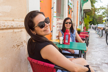 friends talking, enjoying and smiling at a restaurant table, women friends going away for the weekend. 