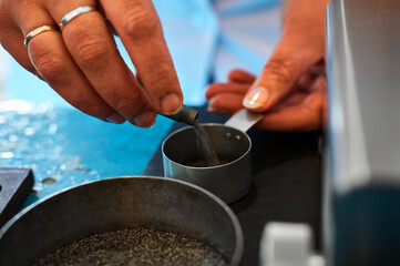 Worker pours gunpowder into metal bowl on table at factory