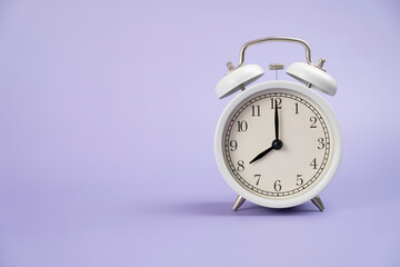 Retro alarm clock on purple or violet table background, vintage style, flat lay