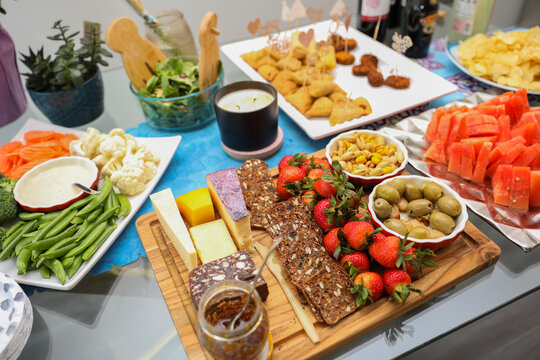 elegantly arranged charcuterie board displaying various meats, cheeses, fruits, and nuts. It symbolizes the joy of abundance and shared experiences, emphasizing the importance of enjoying life