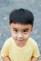 Portrait of an Asian boy wearing a yellow t-shirt. Blurred background.