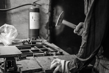 A man works with a hammer in a workshop.