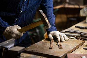 A man works with a hammer in a workshop.