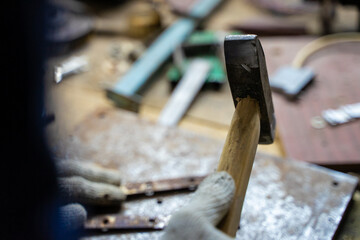 A man works with a hammer in a workshop.