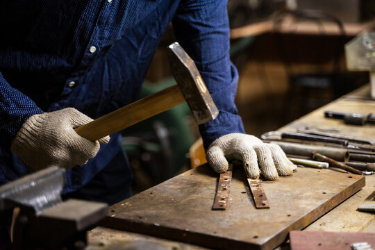 A man works with a hammer in a workshop.
