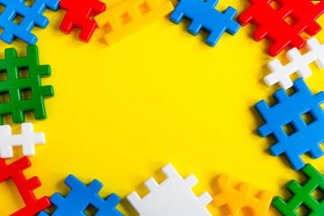 Obraz premium Baby kids toy frame. Top view of a composition of colourful constructor parts on a yellow background. Blocks flat layer. Copy spase for text
