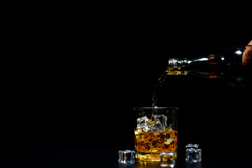 Pouring alcohol into glass, black background