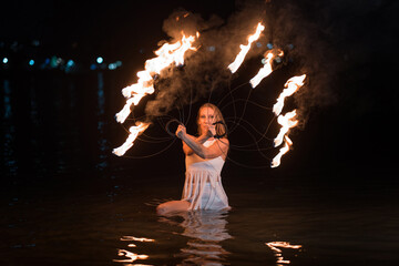 Caucasian woman dancing with fire in the water. Fire show at sea. Acrobatics on the beach. Yoga and relaxation at sunset. Spectacular circus performance. model body. High quality FullHD footage.  © aaalll3110