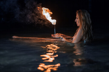 Caucasian woman dancing with fire in the water. Fire show at sea. Acrobatics on the beach. Yoga and relaxation at sunset. Spectacular circus performance. model body. High quality FullHD footage.  © aaalll3110