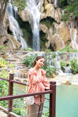 Fototapeta na wymiar Young Asian woman standing on the wooden walkway in the Kuang Si Waterfall Popular attractions of Lung Prabang, Laos