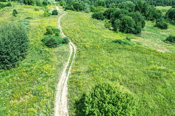 Fototapeta na wymiar winding country road among green meadow. summer countryside landscape in sunny day. drone photo.
