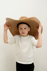 Little boy kid wearing summer hat and hawaiian swimsuit clueless and confused expression with arms and hands raised. doubt concept. . High quality photo