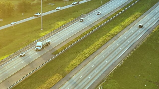 High angle view of wide congested american highway with many driving cars and trucks at sunset. Concept of interstate transportation system