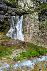 Fototapeta premium The waterfall in the tropical mountains. The alpine mountains and meadows.