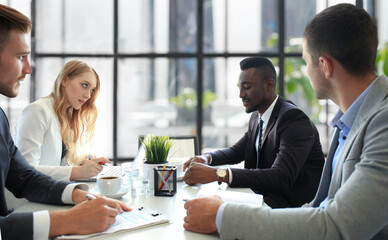 Business people in discussing something while sitting together at the table.