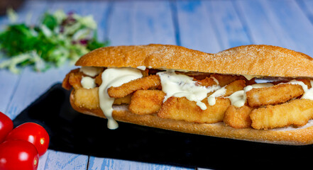 typical squid sandwich with mayonnaise Madrid, Spain, on a black slate with salad and cherry tomatoes