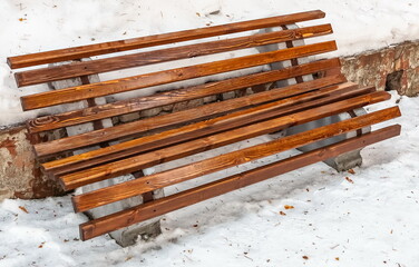 Wooden bench close-up on the background of snow in winter
