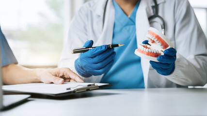 Young Male dentist holding tooth model.