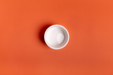 Empty white plate from above on orange background.