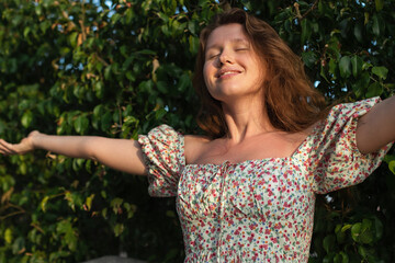 Portrait of beautiful young woman in dress is enjoy summer or spring day on natural green natural wall background in garden or forest on nature