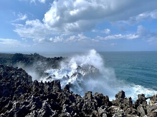 Capture of the light sea blue waves of the Indian Ocean crashing against the jagged limestone edges. Sun falling on the limestones adding a shine. Cloudy Skies