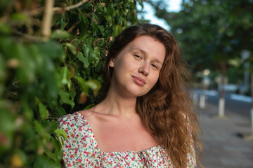 Portrait of beautiful young woman in dress is enjoy summer or spring day on natural green natural wall background in garden or forest on nature