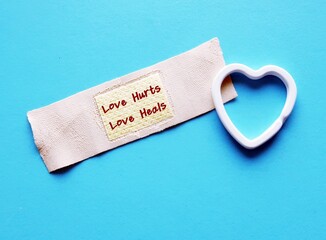 Hearts on band aid plaster with handwritten text LOVE HURTS LOVE HEALS, concept of healing a broken...