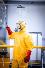 Accident in chemicals production plant. Worker in protection suit and gas mask taking a quick...
