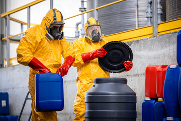 Teamwork in chemical factory. Workers in protection suit and gas masks mixing chemicals and making...