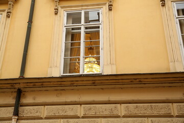 Crystal chandelier burns in the window opening, view from the street