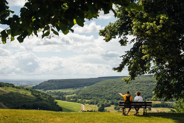 Un couple assis sur un banc admirant un paysage de Bourgogne. Des touristes sur un banc regardant le paysage. A l'ombre d'un arbre, un couple se repose face à un panorama.