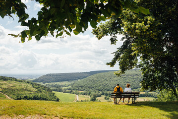 Un couple assis sur un banc admirant un paysage de Bourgogne. Des touristes sur un banc regardant le paysage. A l'ombre d'un arbre, un couple se repose face à un panorama.