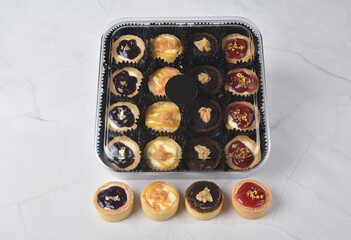 mini bake cute crisp creamtart with colourful flavour like chocolate coffee walnut, golden blueberry, strawberry osmanthus, mango vanilla in crystal plastic box on white marble pastry halal party menu