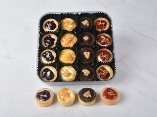 mini bake cute crisp creamtart with colourful flavour like chocolate coffee walnut, golden blueberry, strawberry osmanthus, mango vanilla in crystal plastic box on white marble pastry halal party menu
