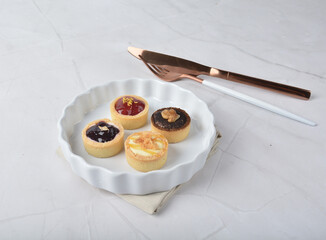 mini bake cute crisp creamtart with colourful flavour like chocolate coffee walnut, golden blueberry, strawberry osmanthus, mango vanilla in crystal plastic box on white marble pastry halal party menu
