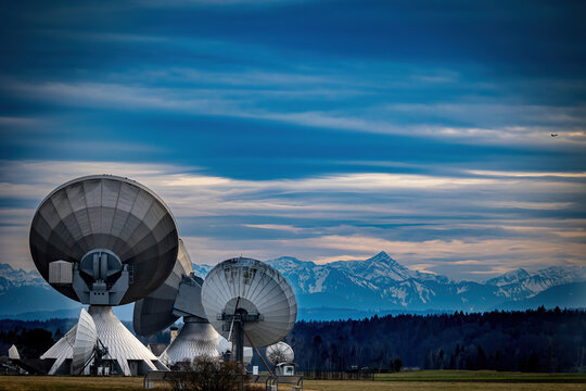 Kommunikation ins Weltall über die Erdfunkstelle in Bayern. Im Hintergrund die bayerische Alpen mit einem ankommenden Wetterwechsel. 