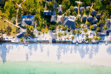Fototapeta na wymiar Immerse yourself in the natural beauty of Zanzibar Island's tropical beach, with its white sand, swaying palm trees, and crystal-clear turquoise waters against a blue sky with fluffy clouds on a sunny