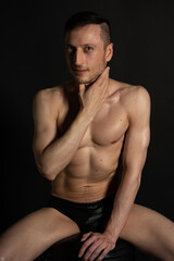 Fototapeta premium Adult attractive man with a beautiful body posing in the studio. Black background.