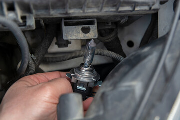Fototapeta premium A man hold car headlights and and inserted into the headlight to replace the broken bulb in engine room : Replacing the headlight bulbs of the car itself service concept
