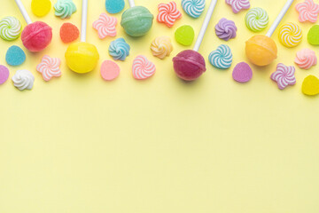 Fototapeta na wymiar Sweet lollipops and candies on yellow background