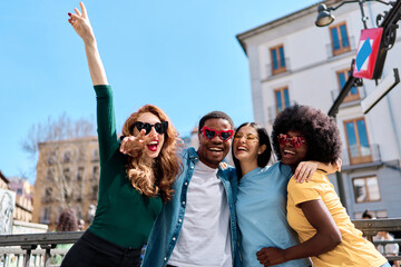 Excited multiethnic friends joking with heart shape sunglasses outdoors