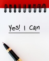 Notebook on red  background with text YES I CAN, concept of self talk or affirmation to boost power...