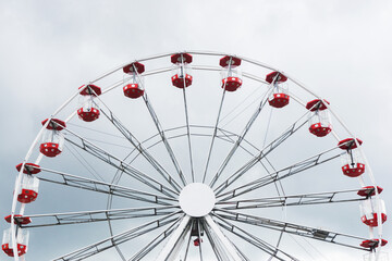 Ferris wheel amusment park. Stormy clouds in the background. Rainy weather ruining festival day in fun park. Funfair adventure background.	