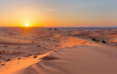 Naklejka na ściany i meble Sunset over the sand dunes in the desert. Arid landscape of the Sahara desert