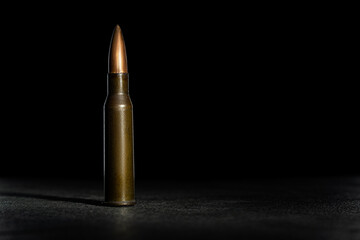Rifle bullet long cartridge on black background. Army or hunting weapon shot object, violence and danger symbol.